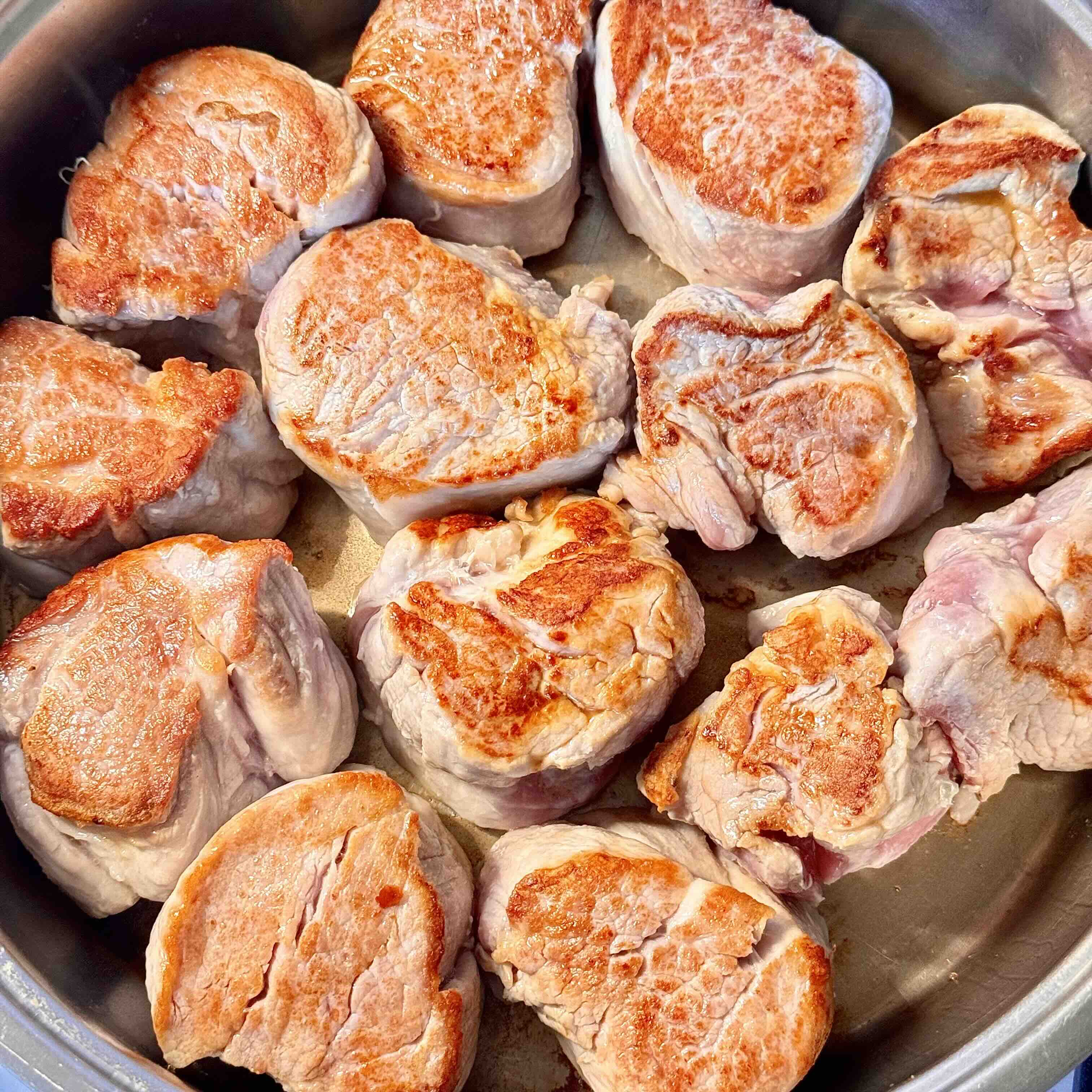 Golden-brown seared pork tenderloin on a plate.