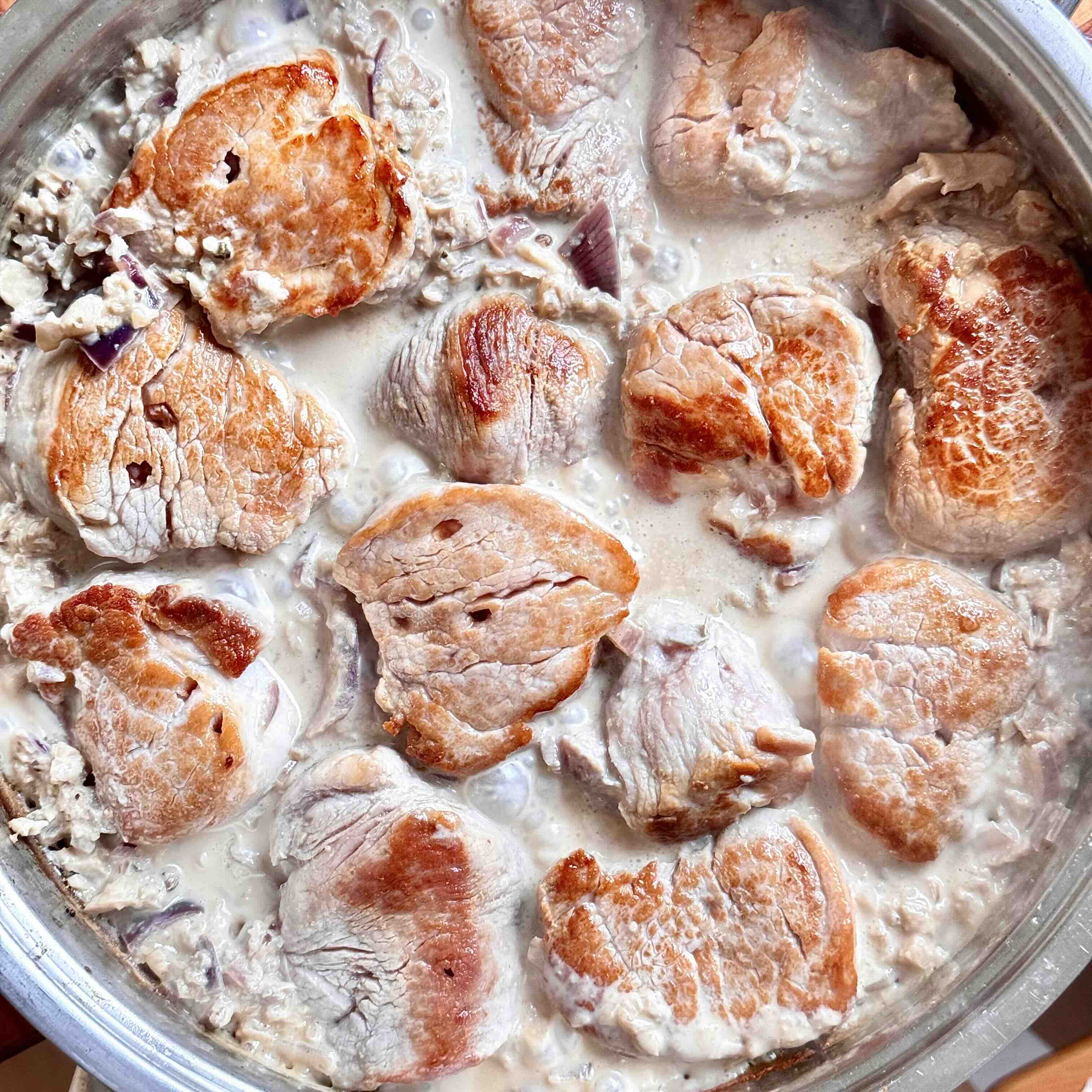 Pork tenderloin simmering in creamy sauce with mushrooms.