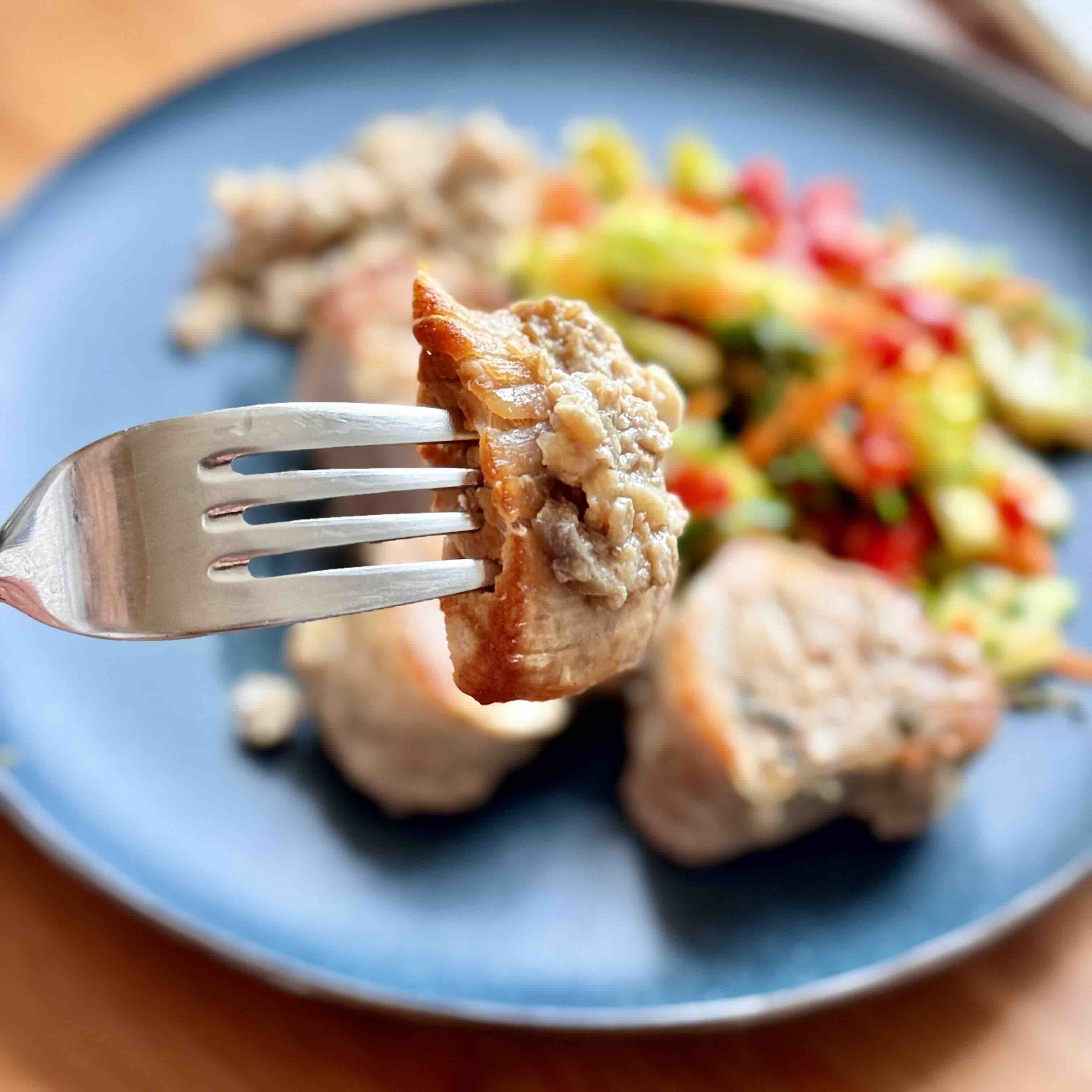 Finished creamy pork tenderloin garnished with salad from green vegetables.