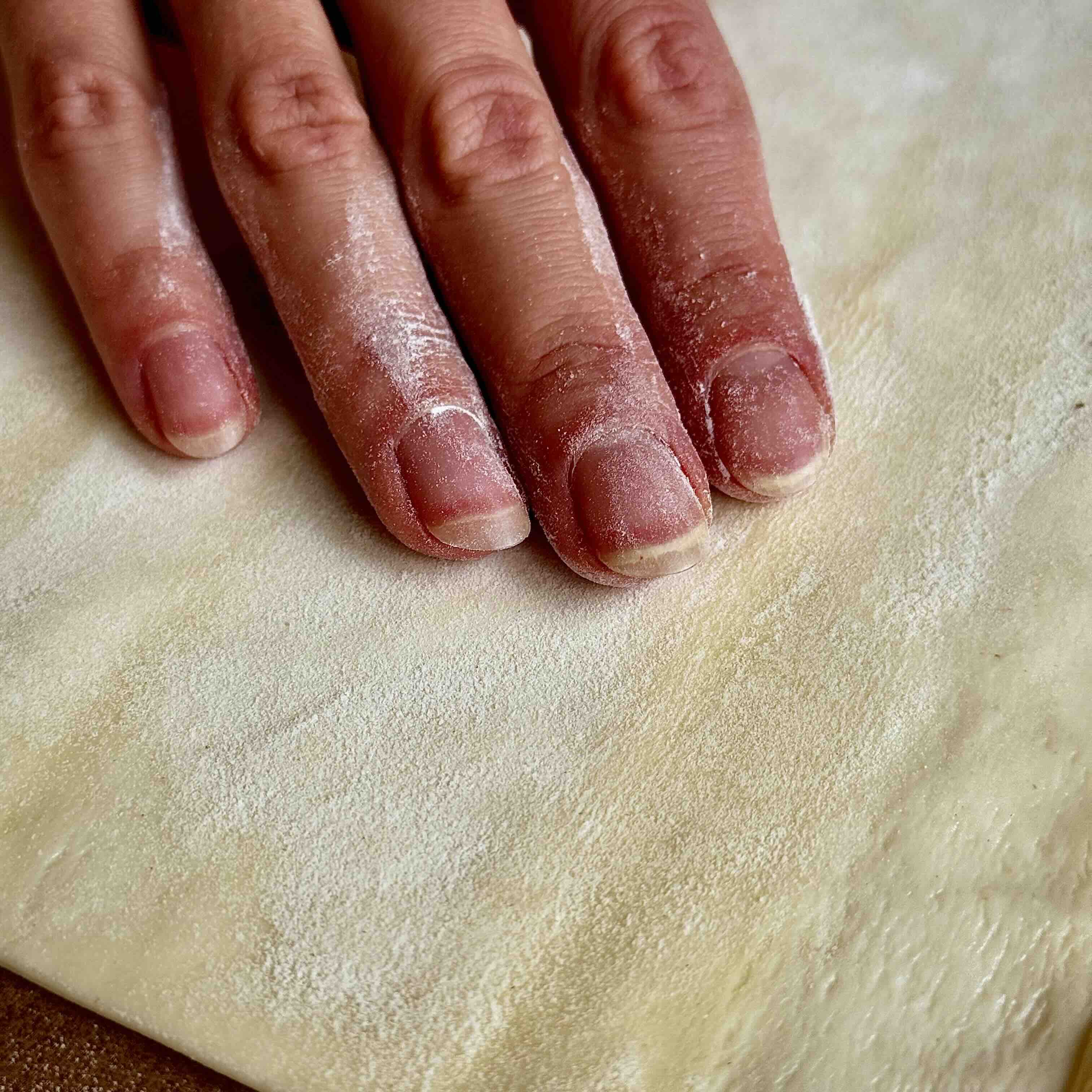 A rolled puff pastry sheet on a parchment-lined tray with fork marks