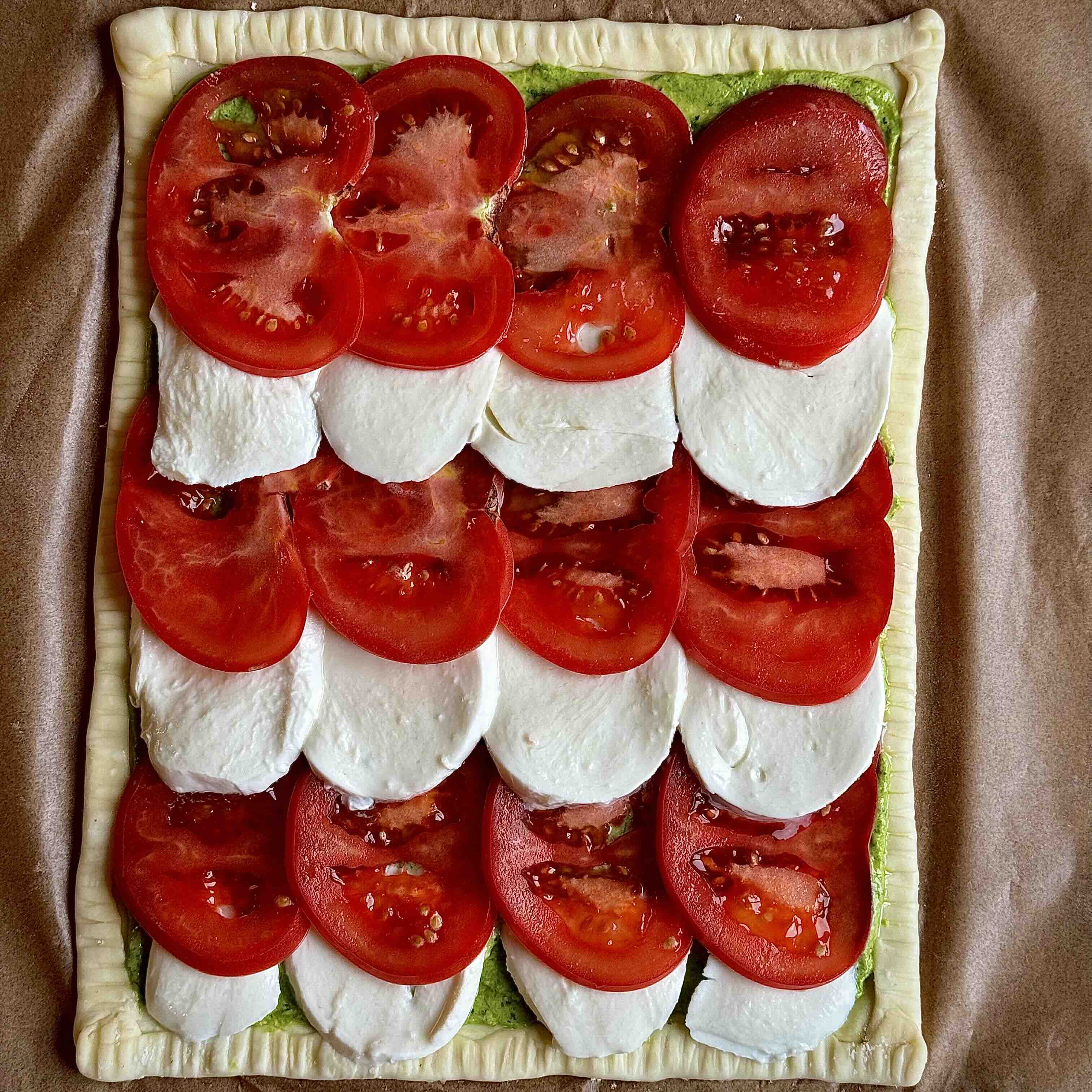 Alternating slices of tomato and mozzarella arranged neatly on the pastry.