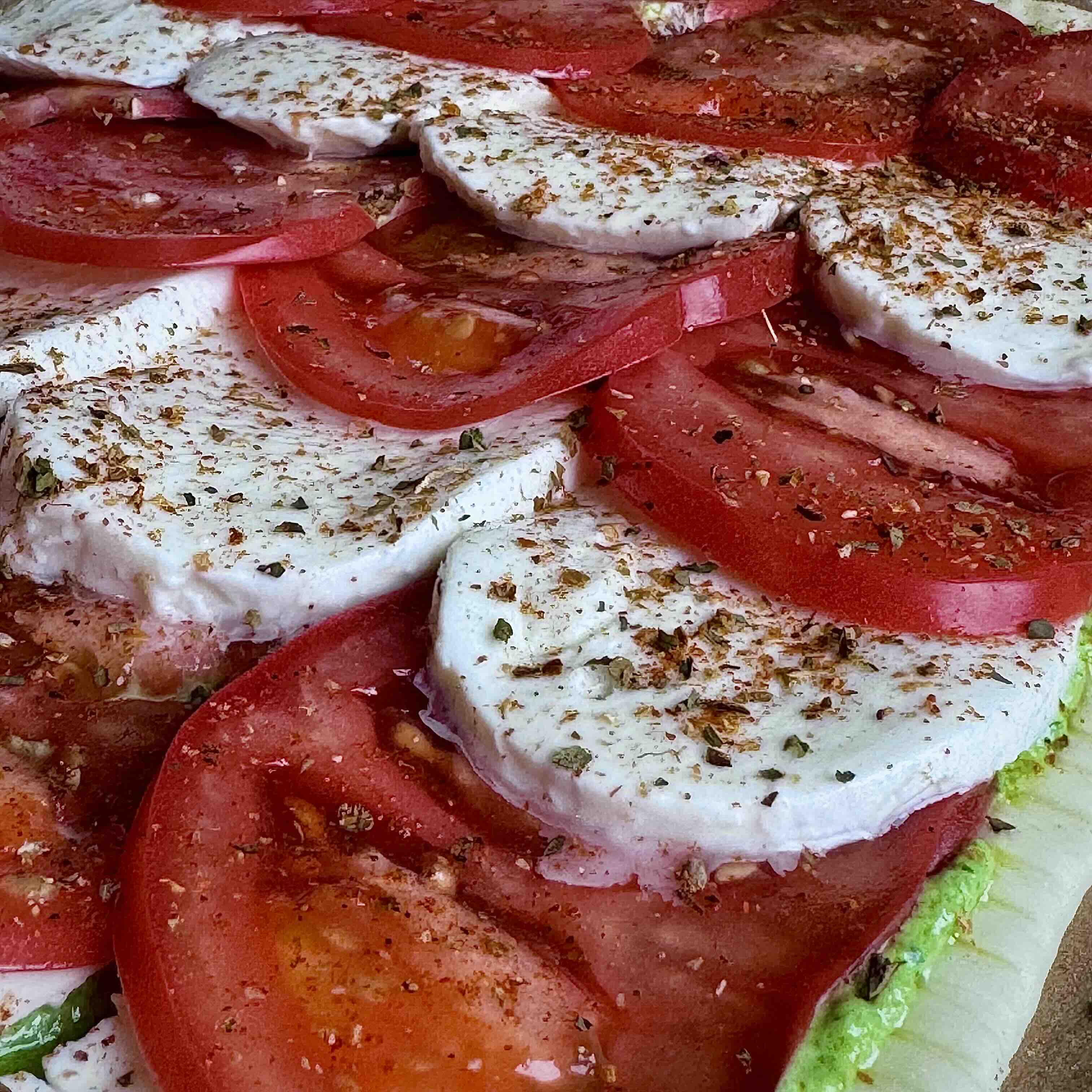 A drizzle of olive oil being added to the pizza before baking.